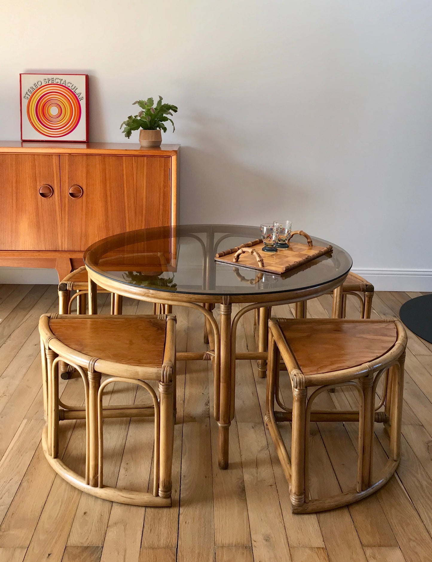 Ensemble en rotin design composé d'une table basse ronde avec plateau en verre fumé et 4 tabourets années 60