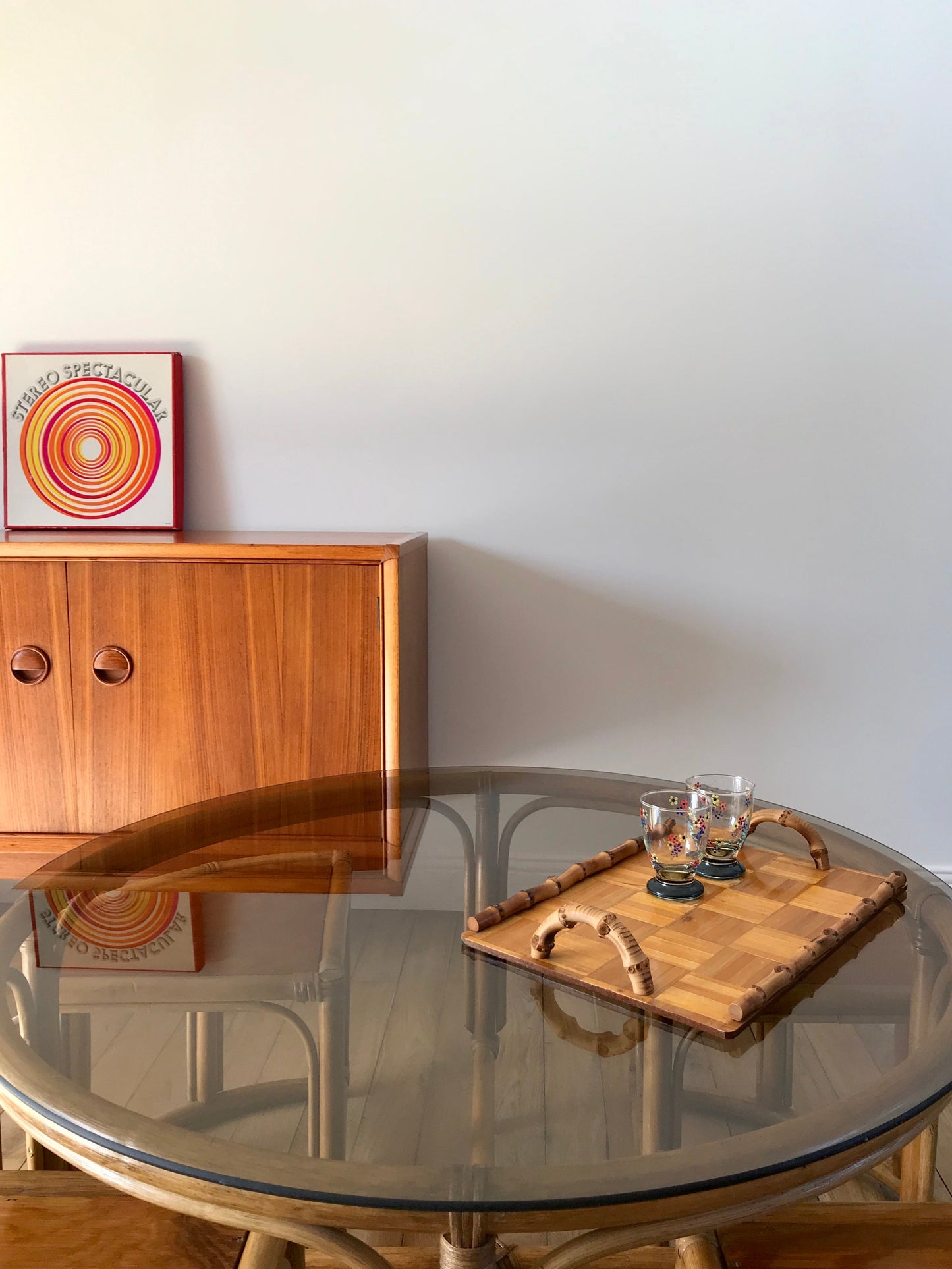 Ensemble en rotin design composé d'une table basse ronde avec plateau en verre fumé et 4 tabourets années 60
