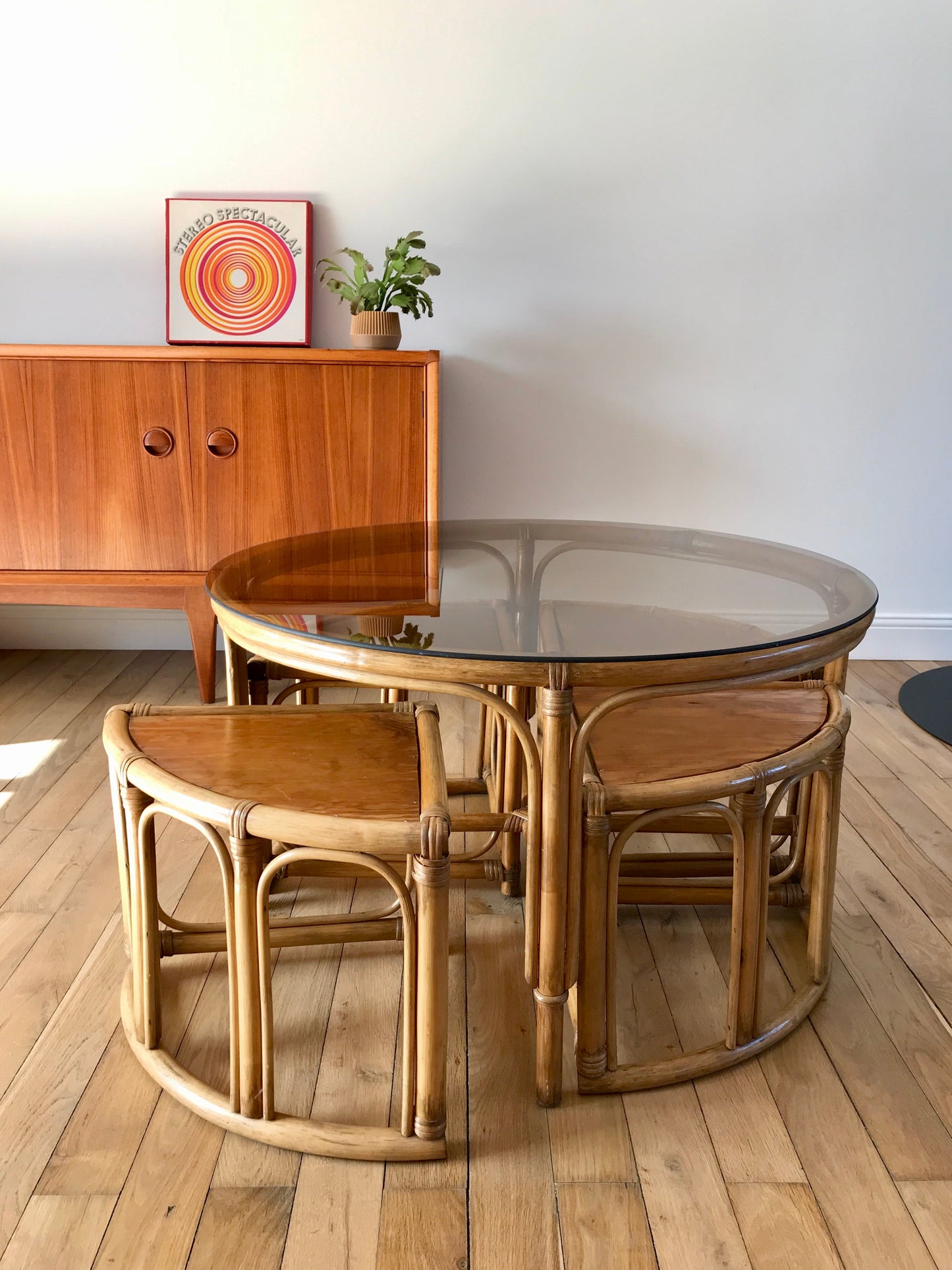 Ensemble en rotin design composé d'une table basse ronde avec plateau en verre fumé et 4 tabourets années 60