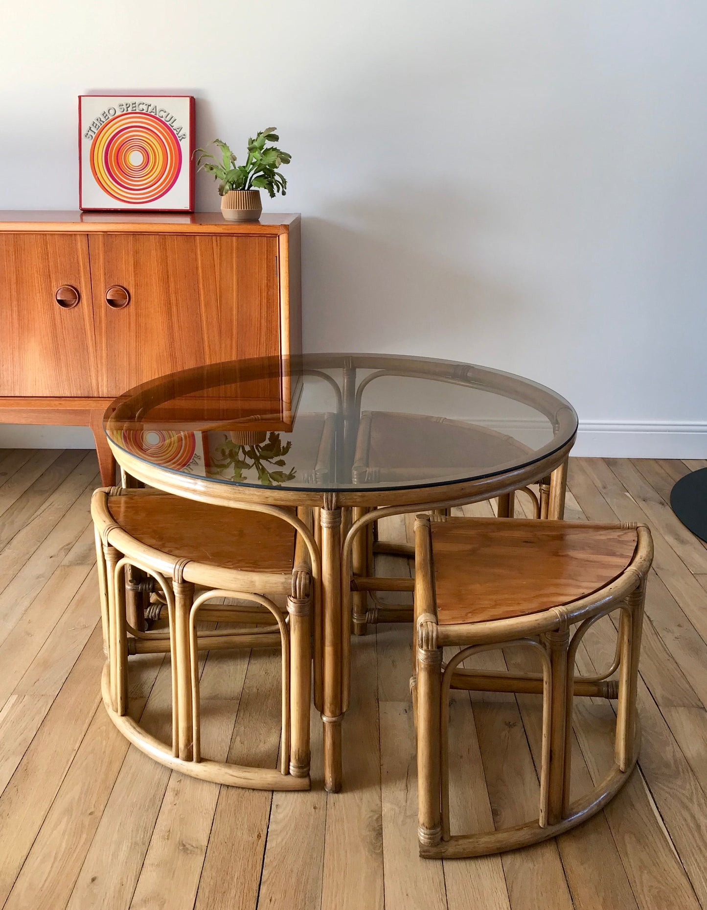 Ensemble en rotin design composé d'une table basse ronde avec plateau en verre fumé et 4 tabourets années 60