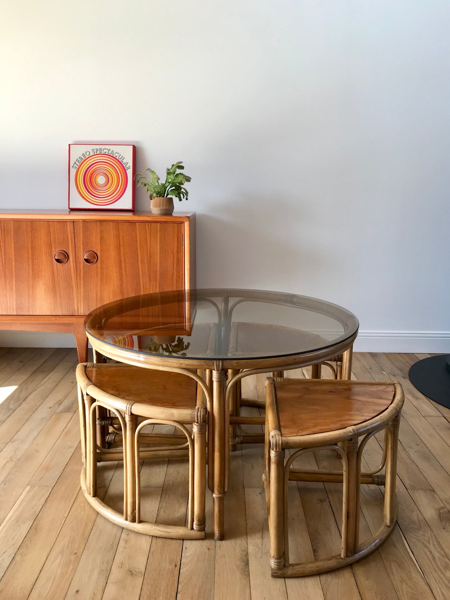 Ensemble en rotin design composé d'une table basse ronde avec plateau en verre fumé et 4 tabourets années 60