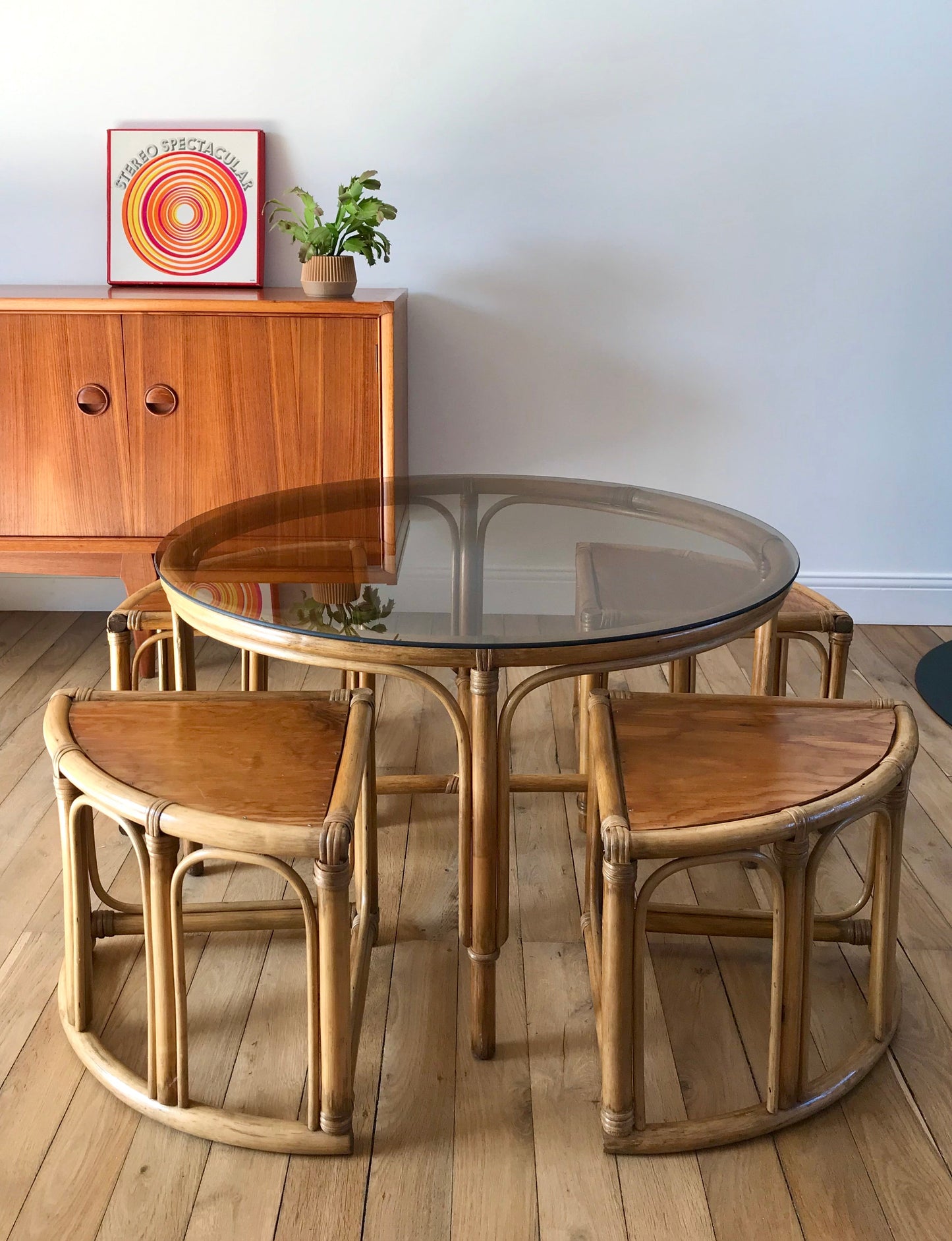 Ensemble en rotin design composé d'une table basse ronde avec plateau en verre fumé et 4 tabourets années 60
