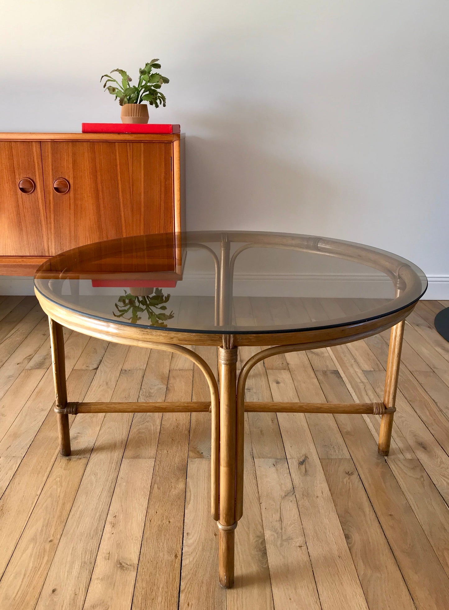 Ensemble en rotin design composé d'une table basse ronde avec plateau en verre fumé et 4 tabourets années 60