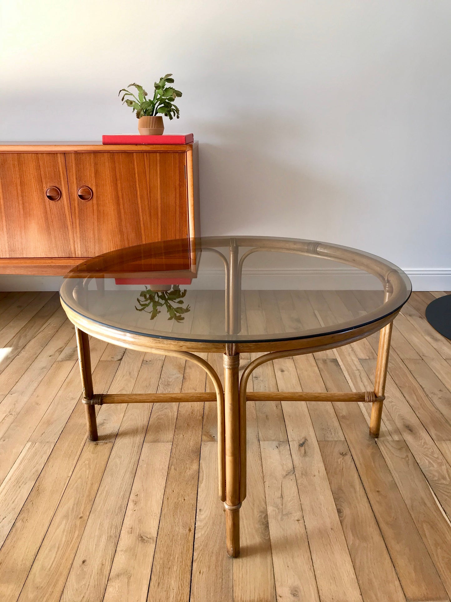 Ensemble en rotin design composé d'une table basse ronde avec plateau en verre fumé et 4 tabourets années 60