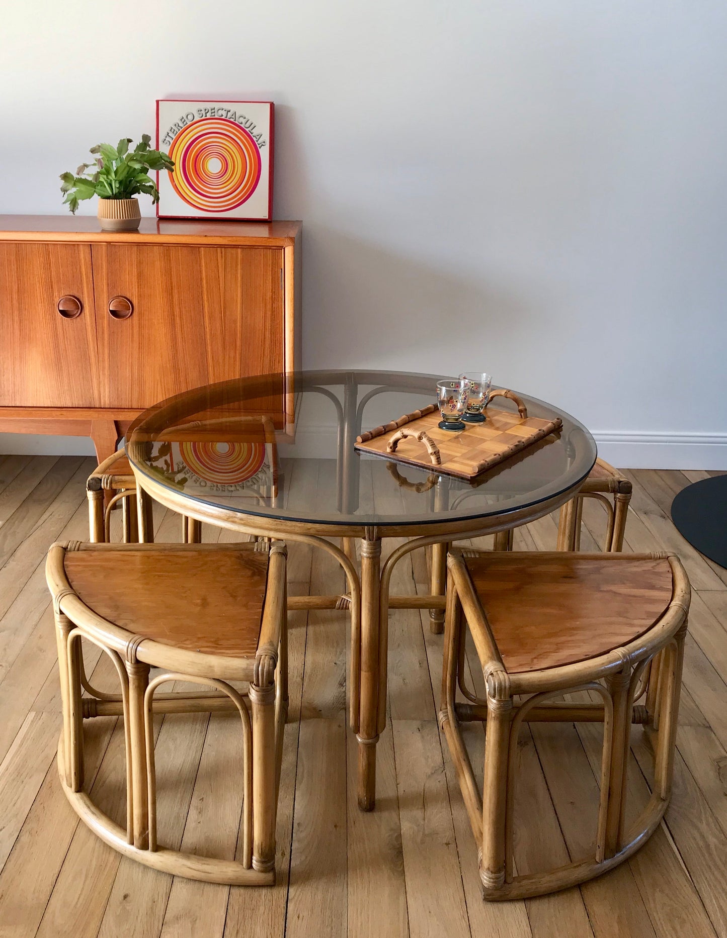 Ensemble en rotin design composé d'une table basse ronde avec plateau en verre fumé et 4 tabourets années 60
