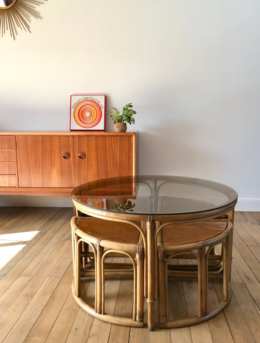 Ensemble en rotin design composé d'une table basse ronde avec plateau en verre fumé et 4 tabourets années 60